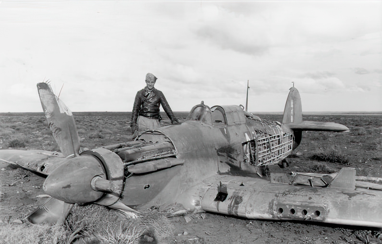 Hans-Joachim Marseille standing next to one of his aerial victories, a Hurricane Mk IIB, possibly of No. 213 Squadron RAF, February 1942.[47] There may be sufficient remains on the code to identify it as a No. 274 Squadron RAF aircraft