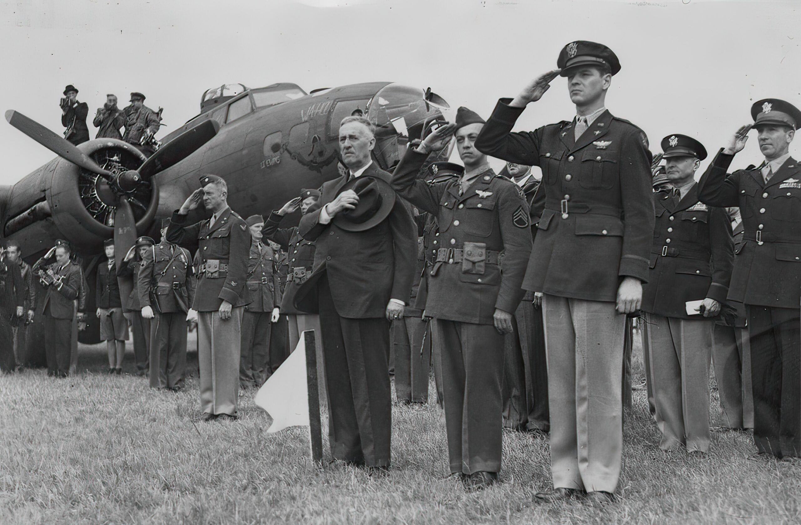 Staff Sergeant Maynard Smith, Secretary of War Henry L Stimson and personnel of the 306th Bomb Group salute in front of a B-17 Flying Fortress, during a medal ceremony at Thurleigh. Passed for publication 16 Jul 1943